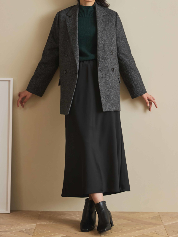 グレーのジャコットに黒のロングスカートを合わせた秋冬コーディネートの女性